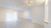 Located at 7550 Stirling Rd in Davie, Florida, this single-story residence offers a clean, functional layout with a bright and neutral interior throughout. The main living area is finished with large white ceramic floor tiles that reflect natural light, complemented by a textured ceiling and a multi-bulb track light fixture. Vertical blinds cover a sliding glass door, allowing for adjustable natural light and outdoor access. The space flows seamlessly into an open secondary area, also finished in the same white tile flooring, creating a cohesive and airy feel. The kitchen is equipped with white cabinetry, warm-toned laminate countertops, a dishwasher, and an electric range, providing a practical and well-organized workspace. The bedrooms feature plush carpeting and are filled with natural light from multiple windows fitted with horizontal blinds. One bedroom offers generous storage with dual louvered bi-fold closets. Additional utility space is present with built-in shelving and ceiling HVAC access. The bathroom is clean and straightforward, featuring a tiled tub-shower combination, a toilet, and a vanity with ample counter space. Overall, the residence presents a bright, move-in ready interior with a practical and efficient floor plan.