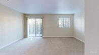 Located in Edmonds, Washington, this one-bedroom unit offers a well-organized, single-floor layout designed to maximize every square foot of available space. The main living area is bright and open, featuring soft wall-to-wall carpeting, neutral beige tones, and a ceiling fan with integrated lighting. A sliding glass door dressed with vertical blinds fills the room with natural light and provides access to an outdoor view, while an additional window with horizontal blinds further enhances the sense of openness. The kitchen is defined by warm wood cabinetry and a granite-topped breakfast bar that separates it from the living space, creating a functional semi-open concept. The bedroom is a comfortable, carpeted room with its own window fitted with horizontal blinds, allowing for controlled natural light. A closet with sliding doors provides convenient storage directly off the main living area. The hallway connects the rooms efficiently, with a bathroom accessible along the corridor. Hardwood-style flooring is featured in the kitchen and bathroom transition areas, contrasting with the plush carpet of the living and sleeping spaces. Clean white trim and a neutral color palette throughout give the unit a fresh, move-in-ready feel suited for everyday living in the Edmonds community.
