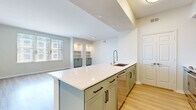Located on McKinney Avenue in the heart of Dallas's sought-after Uptown district, this thoughtfully designed one-bedroom, one-bathroom residence offers a clean, contemporary aesthetic throughout. The open-concept kitchen and living area serves as the centerpiece of the home, anchored by a generously sized kitchen island with a crisp white quartz countertop, sage green cabinetry with matte black hardware, and a stainless steel sink with a professional-style faucet. Stainless steel appliances, including a refrigerator, range, and built-in microwave, complete the modern kitchen. Light wood-toned flooring flows seamlessly throughout the entire space, enhancing the bright and airy atmosphere. The living area is bathed in natural light from large windows offering city views, and features built-in shelving with cabinet storage—an ideal accent for display or organization. The spacious bedroom includes a ceiling fan, ample room for furnishings, and direct access to a dedicated closet. The full bathroom is finished in crisp white tile, featuring a soaking tub and shower combination with a window for natural light. An in-unit laundry area adds everyday convenience, rounding out this well-appointed urban residence.