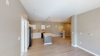 This single-floor residence offers a thoughtfully designed open-concept layout that seamlessly connects the kitchen, dining, and living areas. The kitchen is a standout feature, equipped with white shaker-style cabinetry, granite countertops, a subway tile backsplash, a central island with seating, pendant lighting, and a full suite of black appliances including a refrigerator, range, microwave, and dishwasher. Light hardwood-style flooring runs throughout the main living areas, complementing the neutral gray-toned walls and white trim for a clean, contemporary aesthetic. The living area is open and versatile, with recessed lighting and ample wall space. Two carpeted bedrooms each include a ceiling fan and natural light from windows with blinds. The primary bedroom connects to a generously sized walk-in closet outfitted with wire shelving and hanging rods for organized storage. The primary bathroom features a soaking tub with shower, a wide vanity with granite countertops, white cabinetry, and hardwood-style flooring. A second full bathroom mirrors the same refined finishes, including a tub-shower combination and granite vanity. The overall ambiance is bright, clean, and move-in ready.