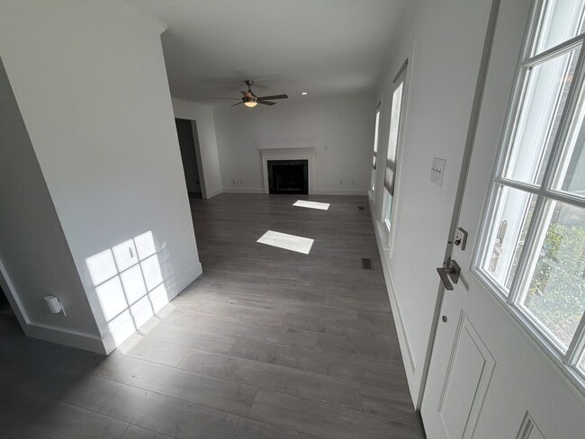 Sunny living room with fireplace, ceiling fan, and can lights. - 115 Waterfall Ct