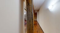 Located at 110 S 15th St in Richmond, VA, this two-bedroom, two-bathroom unit spans two floors and masterfully balances historic industrial character with contemporary finishes. The main floor hosts a combined living, dining, and kitchen area that immediately impresses with its exposed original timber beams, soaring ceilings with visible ductwork, and richly toned hardwood floors. The kitchen is well-appointed with dark cabinetry, granite countertops, stainless steel appliances including a refrigerator, range, microwave, and dishwasher, and pendant lighting above the counter peninsula. Exposed brick walls and a staircase with a skylight overhead add dramatic architectural interest to this open living space. A stacked washer and dryer unit provides in-unit laundry convenience. Upstairs, the two bedrooms continue the warm hardwood flooring and feature ample natural light, with glass railings offering visual connectivity between floors. The hallway showcases a striking original timber post alongside exposed brick, reinforcing the building's storied history. Both bathrooms are finished with tile flooring and dark modern vanities, with one featuring a tub-shower combination. Two closets and additional storage complement the thoughtful layout of this character-rich urban residence.
