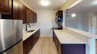 This well-appointed one-bedroom, one-bathroom unit at 1155 Livingston Ave in North Brunswick, NJ offers a thoughtfully designed single-floor layout with modern updates throughout. The open living area is bright and welcoming, featuring durable hardwood-style flooring, neutral walls, and multiple windows fitted with blinds that invite natural light while offering privacy. A baseboard heating system runs along the perimeter, ensuring year-round comfort. The kitchen is a standout feature, showcasing rich dark cabinetry, crisp light countertops, a subway tile backsplash, and stainless steel appliances including a refrigerator and range. A peninsula with pendant lighting connects the kitchen to the living space, offering additional counter seating and an open, airy feel. The bedroom is a calm, generously sized retreat with the same hardwood-style flooring, clean white walls, and a dedicated closet with built-in shelving for organized storage. The bathroom is finished with large-format stone-look wall tiles surrounding a soaking tub, complemented by matte black fixtures that add a contemporary touch. The overall aesthetic is clean, modern, and move-in ready, making this an attractive and functional home in North Brunswick.