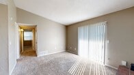 Located at 12901 S Western Ave in Oklahoma City, this 2-bedroom, 1-bathroom residence offers a well-planned single-floor layout. The living room serves as the heart of the home, featuring a charming brick-hearth fireplace and a large sliding glass door dressed with vertical blinds that floods the space with natural light and provides outdoor views. Soft carpeting runs throughout the living areas and bedrooms, lending a warm and comfortable feel.

The galley-style kitchen is efficiently designed with grey cabinetry, granite-look countertops, hardwood-style flooring, and black appliances including a refrigerator and electric range. A pendant chandelier illuminates the adjacent dining area, which opens seamlessly to the kitchen.

Both bedrooms are carpeted and feature neutral toned walls. The primary bedroom includes a spacious bi-fold closet, while the secondary bedroom offers a window with natural light. The full bathroom is well-appointed with dual sinks set in a granite-look vanity, teal cabinetry, hardwood-style flooring, and a large mirror with overhead lighting. Textured ceilings are present throughout. The layout is compact yet functional, making efficient use of every area of the home.