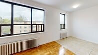 Located on the fourth floor at 510 Dawes Rd in Toronto's east end, this one-bedroom, one-bathroom unit offers a practical and efficiently designed layout. The main living area is characterized by warm parquet wood flooring laid in a classic basket-weave pattern, crisp white walls, and large black-framed windows that invite an abundance of natural light while framing views of the surrounding neighbourhood. A classic cast-iron radiator provides reliable in-unit heating, adding a touch of vintage character to the space. The entry area transitions seamlessly into the open living space, with tile flooring near the front door giving way to the warm wood parquet throughout. The bedroom features a built-in sliding-door closet offering convenient storage, and a window that brings in additional natural light. The bathroom is finished with white square wall tiles accented by a bold black border, a full bathtub with shower, a pedestal-style sink with grey cabinetry, tile flooring, and a classic cast-iron radiator. The overall aesthetic is clean and functional, with a neutral palette that provides a versatile base for personalization.