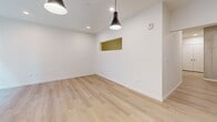 Located at 955 Bannock St in Denver's vibrant Golden Triangle neighborhood, this one-bedroom, one-bathroom unit offers a thoughtfully designed open layout with a clean, contemporary aesthetic throughout. Light-toned hardwood flooring runs throughout the main living areas and bedroom, creating a warm and cohesive feel. The open living area features crisp white walls, recessed lighting, and bold pendant light fixtures, along with a distinctive accent niche that adds a touch of visual interest. A pass-through window connects the living space to adjacent areas, enhancing the sense of openness. The kitchen is equipped with stainless steel appliances, white cabinetry, and marble-style countertops, reflecting a modern and functional design. The spacious bedroom features a closet with sliding doors and a horizontal clerestory window that allows natural light while maintaining privacy. The bathroom is finished with large-format white tile flooring, a white vanity with marble countertops, matte black hardware and fixtures, and a full-width mirror, lending a sleek and polished look. The overall design palette of whites, light woods, and black accents gives the space a refined, contemporary character well-suited to urban Denver living.
