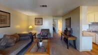 Located at Meadowood Mall Circle in Reno, Nevada, this single-floor residence offers a well-organized layout that flows naturally from room to room. The galley-style kitchen is outfitted with white cabinetry, a tile backsplash, a coil-burner electric range, a full-size refrigerator, and a stainless steel sink — all set atop warm hardwood flooring that extends into the adjacent dining area. The dining space features a sliding window overlooking a landscaped outdoor area, filling the room with natural light, and is paired with a ceiling fan for added comfort. The living room is carpeted and generously proportioned, offering a relaxed atmosphere with textured ceilings and a hallway connecting to the private areas of the home. The bedroom is a calm retreat, finished with carpet, a textured ceiling, and a large sliding window that brings in natural light and outdoor views of surrounding greenery. The bathroom is accessed via a hardwood-floored hallway and includes a vanity with a mirrored medicine cabinet and a shower-tub combination. Throughout the residence, warm neutral wall tones and consistent finishes create a cohesive and inviting atmosphere suitable for everyday living.