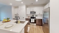 Located at 720 River Hwy in Mooresville, NC, this well-appointed one-bedroom, two-bathroom residence offers a thoughtfully designed single-level layout with modern finishes throughout. The open-concept kitchen and living area serves as the heart of the home, featuring a large center island with a quartz countertop, an undermount sink with a matte black faucet, white shaker-style upper cabinetry, contrasting dark lower cabinets, a subway tile backsplash, and stainless steel appliances including a refrigerator, range, and microwave. Pendant and recessed lighting add a polished touch to the space. The living room is bright and airy, showcasing vaulted ceilings, light hardwood-style flooring, a ceiling fan, and French doors that open to an outdoor balcony, filling the space with natural light and outdoor views. The generously sized bedroom is carpeted with neutral tones, features multiple windows with outdoor views, and includes a ceiling fan for comfort. The bathrooms are clean and modern, with one featuring a soaking tub-shower combo adorned with white subway tile and built-in corner shelving. A dedicated laundry room with a full-size washer and dryer completes this efficient and stylish home.