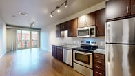 Located at 3029 22nd Ave S in Minneapolis, MN, this one-bedroom, one-bathroom unit offers a well-organized and functional layout across a single floor. The open-concept kitchen and living area serves as the heart of the space, featuring rich dark-wood cabinetry, granite-style countertops, and a full suite of stainless steel appliances including a range, dishwasher, microwave, and refrigerator. Track lighting illuminates the kitchen and living zone, while warm hardwood-style flooring runs throughout the main living areas, lending a cohesive and modern aesthetic. Sliding glass doors lead directly to a private balcony, flooding the living area with natural light and offering open views of the surrounding neighborhood. The bedroom is carpeted for comfort and includes a built-in closet with shelving, as well as a window providing additional natural light. The bathroom features a dark-wood vanity with a white countertop, a framed mirror, and hardwood-style flooring that continues from the hallway. Additional conveniences include a dedicated laundry area and a utility room. The unit's contemporary design, practical storage solutions, and outdoor access make it a well-appointed urban residence in South Minneapolis.