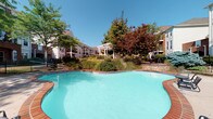 Situated in Dublin, Ohio, this property at 4130 Times Square Blvd offers a well-appointed single-floor layout complemented by impressive outdoor amenities. The standout feature of the community is its expansive resort-style swimming pool, showcasing crystal-clear turquoise water and a gracefully curved design framed by warm brick coping. The pool area is enveloped by lush, mature landscaping, including vibrant ornamental trees and manicured shrubs, creating a serene and private outdoor retreat. A charming pergola with a canopy provides a shaded gathering space, ideal for relaxation and socializing. Surrounding multi-story residential buildings with classic architectural detailing, including balconies and traditional brick and neutral-toned facades, frame the courtyard and contribute to a cohesive, community-oriented atmosphere. The grounds are thoughtfully designed with tiered stone retaining walls and walkways that connect the various outdoor spaces. The overall ambiance is that of a well-maintained, tranquil environment that balances natural greenery with structured architectural elements, offering residents an inviting outdoor living experience in a suburban Dublin setting.