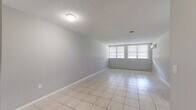 This one-bedroom, one-bathroom unit at 80 Kane St in West Hartford, Connecticut offers a practical and functional layout across a single floor. The living area is generously proportioned, featuring light-toned ceramic tile flooring, neutral gray walls, and a textured ceiling. Large windows allow natural light to fill the space, complemented by a baseboard heating system and a wall-mounted air conditioning unit for year-round comfort.

The galley-style kitchen is efficiently designed, featuring warm-toned wood cabinetry on both sides, light countertops, tile flooring, and black appliances including a refrigerator, dishwasher, and range. A stainless steel sink is positioned along one wall, providing ample workspace within the corridor-style layout.

The bedroom is a well-sized, carpeted room with a window that brings in natural light. It includes a built-in closet with a hanging rod and a wall-mounted AC unit for independent climate control.

The bathroom is thoughtfully appointed with a white vanity, large mirror, mosaic tile flooring in neutral and burgundy tones, and a tiled shower-tub combination. A hallway connects the rooms, contributing to the unit's efficient and cohesive flow throughout.