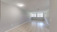 This one-bedroom, one-bathroom unit at 80 Kane St in West Hartford, Connecticut offers a practical and functional layout across a single floor. The living area is generously proportioned, featuring light-toned ceramic tile flooring, neutral gray walls, and a textured ceiling. Large windows allow natural light to fill the space, complemented by a baseboard heating system and a wall-mounted air conditioning unit for year-round comfort.

The galley-style kitchen is efficiently designed, featuring warm-toned wood cabinetry on both sides, light countertops, tile flooring, and black appliances including a refrigerator, dishwasher, and range. A stainless steel sink is positioned along one wall, providing ample workspace within the corridor-style layout.

The bedroom is a well-sized, carpeted room with a window that brings in natural light. It includes a built-in closet with a hanging rod and a wall-mounted AC unit for independent climate control.

The bathroom is thoughtfully appointed with a white vanity, large mirror, mosaic tile flooring in neutral and burgundy tones, and a tiled shower-tub combination. A hallway connects the rooms, contributing to the unit's efficient and cohesive flow throughout.