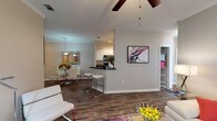 Located at 8100 US 98 in Pensacola, Florida, this single-floor residence offers a thoughtfully designed open-concept layout with modern finishes and a bright, welcoming atmosphere. The living area features rich wood-look flooring, crown molding, a ceiling fan, and large windows that allow abundant natural light to fill the space. A vibrant area rug and generous layout make this room ideal for both relaxing and entertaining.

The dining area flows seamlessly from the living room and is accented by a pendant light fixture, crown molding, and wood-look flooring, creating an intimate yet connected space. Adjacent to the dining area, the kitchen features white cabinetry, dark granite countertops, black appliances, and a breakfast bar with bar seating — combining functionality with contemporary style.

The bedrooms are carpeted and well-proportioned, each featuring ceiling fans and windows dressed with sheer curtains and blinds that invite soft, natural light. One bedroom includes a walk-in closet. A dedicated home office provides a quiet, light-filled workspace with carpet flooring and a large window.

The bathroom is finished with dark granite countertops, white cabinetry, a large vanity mirror with overhead lighting, and a full tub-shower combination with wood-look flooring that ties the space together cohesively throughout.