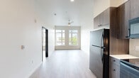 Located at 420 Center St NE in downtown Salem, Oregon, this modern one-bedroom, one-bathroom unit offers a thoughtfully designed open-concept layout with clean, contemporary finishes throughout. Light wood-style flooring runs seamlessly across the entire space, complementing the bright white walls and creating a cohesive, airy aesthetic.

The combined kitchen and living area serves as the heart of the unit. The kitchen is outfitted with dark wood cabinetry extending to the ceiling, white quartz countertops, a tile backsplash, and a full suite of black Whirlpool appliances including a refrigerator, electric range, over-the-range microwave, and dishwasher. A stacked washer and dryer unit is conveniently tucked near the entryway. The living area benefits from a ceiling fan and large dual-pane windows that frame views of the surrounding Salem cityscape and green tree canopy, allowing generous natural light to fill the room.

The bedroom is a calm, well-proportioned retreat featuring its own window with outdoor views and a dedicated closet with built-in shelving. The bathroom is finished in a clean, minimal style with a walk-in shower stall and matte black hardware accents. This unit combines functional urban living with modern design in a prime downtown Salem location.
