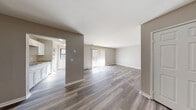 Located at 1300 Georgetown in Lansing, Michigan, this single-floor unit offers a clean, modern aesthetic throughout. The open living area is bathed in natural light streaming through vertical blind-covered sliding glass doors, creating a welcoming and airy atmosphere. Neutral-toned walls and durable wood-look vinyl plank flooring run consistently throughout the space, providing a cohesive and contemporary feel.

The galley-style kitchen is well-appointed with crisp white shaker cabinets, granite-look countertops, a stainless steel sink, and white appliances including a coil-top range and refrigerator. A window at the end of the kitchen allows for additional natural light. Ample upper and lower cabinetry provides generous storage space.

The bedrooms are generously sized with the same vinyl plank flooring, clean white trim, and closet space featuring built-in shelving and hanging rods. The bathroom is neatly finished with a white vanity, granite-look countertop, a medicine cabinet mirror, and a tub-shower combination with a white surround.

Throughout the unit, textured ceilings, neutral warm-gray walls, and consistent flooring tie each room together, resulting in a practical and well-maintained living space.