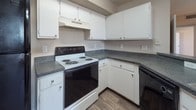 This single-floor unit is designed with a practical and cohesive layout that maximizes comfort and functionality. Wood-look flooring runs throughout the entire space, providing a warm and unified aesthetic from room to room.

The open-concept living area is bright and welcoming, featuring a ceiling fan overhead and a large window dressed with vertical blinds that allows generous natural light to fill the room. The space flows seamlessly into the kitchen, which is separated by a peninsula counter finished with dark granite-style laminate countertops. The kitchen is equipped with white cabinetry, ample counter space, an electric coil range, a dishwasher, and a refrigerator, offering everything needed for everyday cooking.

The unit includes two bedrooms, each outfitted with ceiling fans and windows that bring in natural light. One bedroom features a closet with built-in shelving and a hanging rod, providing practical storage. The neutral wall tones and consistent flooring carry throughout both rooms, creating a calm and understated atmosphere.

Two full bathrooms serve the unit, each featuring a tub-shower combination with white tile surround, wood-look flooring, and a vanity with dark countertops and white cabinetry. The textured ceilings present throughout the home add a classic residential character to the overall design.
