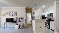 Located in North Little Rock, AR, this 2-bedroom, 1-bathroom residence offers a thoughtfully designed single-floor layout with a warm, neutral color palette throughout. The open living room is a welcoming space featuring plush carpet flooring, crown molding, a ceiling fan with light fixture, and a bright window that allows natural light to filter in, creating an airy atmosphere. The kitchen is efficiently laid out with white cabinetry, granite-style countertops, black appliances including a refrigerator, electric range, and over-the-range microwave, complemented by easy-to-clean tile flooring. A breakfast bar separates the kitchen from the living area, adding to the open feel. The primary bedroom is a comfortable retreat with a ceiling fan, plush carpet, a window with natural light, and a closet for storage. The second bedroom also features carpet flooring and a ceiling fan. The shared full bathroom includes a single vanity with granite-style countertops, white cabinetry, a large mirror, and a shower/tub combination. Additional closet storage is available within the unit, providing practical organization solutions throughout this cozy and functional North Little Rock residence.
