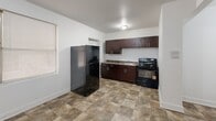 Located on S Wabash Ave in Chicago's South Side, this two-bedroom, one-bathroom unit offers a practical and straightforward layout across a single floor. A hallway connects the main areas, leading into a well-proportioned kitchen finished with rich dark-brown cabinetry, granite-look countertops, a sink, and black appliances including a full-size refrigerator and gas range. Stone-pattern tile flooring runs through the kitchen and hallway, providing a durable surface in high-traffic areas. Both bedrooms feature wall-to-wall carpeting, white-painted walls, and windows fitted with blinds that allow natural light to filter in. The primary bedroom is generously sized relative to the overall footprint, and both rooms are equipped with classic cast-iron radiators, reflecting the building's traditional heating system. The bathroom is clean and functional, featuring light tile flooring, a white vanity with cabinet storage, a medicine cabinet with mirror, and a tiled tub-shower combination. The overall aesthetic is clean and neutral throughout, with bright white walls and flush-mount ceiling lighting providing a simple, move-in-ready environment suited for everyday living in a well-established Chicago neighborhood.