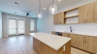 Located at 500 E Rivulon Blvd in Gilbert, Arizona, this thoughtfully designed 2-bedroom, 2-bathroom residence offers a seamless blend of modern aesthetics and functional living. The open-concept kitchen and living area serves as the heart of the home, showcasing warm wood-tone cabinetry, a white quartz waterfall island, subway tile backsplash, stainless steel appliances, and elegant glass pendant lighting — all set atop light-toned hardwood flooring. A ceiling fan and generous windows fill the living space with natural light.

Both bedrooms feature plush carpeting, large windows with outdoor views, and dedicated closets — including a well-organized walk-in closet with built-in shelving and hanging rods. The primary bedroom opens directly to a private balcony through sliding glass doors. Each bathroom is finished with wood-grain vanities, white quartz countertops, and matte black fixtures. The primary bath includes a glass-enclosed walk-in shower, while the secondary bath features a long double-vanity layout.

Additional highlights include a dedicated laundry area, a pantry, and four closets providing exceptional storage. The overall ambiance is clean, contemporary, and bright throughout.