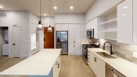 Located at 1680 E Gene Autry Way in Anaheim, California, this modern single-floor residence showcases a clean, contemporary design throughout. Polished concrete floors run seamlessly across the entire unit, lending an industrial-chic aesthetic that complements the bright, neutral color palette.

The kitchen is a standout feature, equipped with stainless steel appliances including a gas range, built-in microwave, French door refrigerator, and dishwasher. Crisp white flat-front cabinetry extends to the ceiling, maximizing storage, while a textured tile backsplash adds subtle visual interest. A large center island with a white countertop provides generous prep space and a natural gathering point. Stylish cone-shaped pendant lights hang above the island, enhancing the modern ambiance.

The bedroom offers impressive ceiling height, a ceiling fan with light fixture, and windows with blinds that invite natural light. It connects directly to a dedicated walk-in closet outfitted with wire shelving and hanging rods for organized storage.

The bathroom is finished in a clean, all-white palette featuring a soaking tub with shower combination, a wide vanity with white cabinetry and quartz-style countertop, a large mirror, and matte black hardware accents throughout. Recessed lighting keeps the space bright and functional.

The overall design of this unit reflects a minimalist, urban sensibility with high-quality finishes and thoughtful details throughout.
