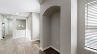 This single-floor residence in Tampa, Florida offers a well-designed layout with a cohesive neutral color palette throughout. The open living and dining area is anchored by rich, wood-look plank flooring that extends through the main living spaces, while a ceiling fan provides year-round comfort. Large sliding glass doors and multiple windows flood the area with natural light, and a distinctive arched wall niche adds an elegant architectural touch. The kitchen is outfitted with crisp white shaker cabinetry, white quartz-style countertops, and stainless steel appliances including a range, over-the-range microwave, and dishwasher, along with a decorative lattice display cabinet for added character. A connecting hallway features the same wood-look flooring, pendant lighting, and a barn-style sliding door, contributing to the home's modern yet warm aesthetic. The bathroom is generously sized, featuring a long white vanity with undermount sink, expansive mirror with recessed lighting, a soaking tub, and a separate glass-enclosed shower. Bedrooms are finished with plush carpeting, neutral walls, and ample space for a variety of furniture arrangements. Overall, this residence presents a clean, move-in ready environment well-suited to comfortable everyday living.
