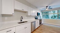 Located in Brookline, MA, this well-appointed 2-bedroom, 2-bathroom apartment spans 1,080 square feet on a single floor. The open-concept kitchen and living area serves as the heart of the unit, featuring white shaker-style cabinetry, light quartz countertops, a stainless steel undermount sink with a matte black faucet, and a full suite of stainless steel appliances including a refrigerator, electric range, over-the-range microwave, and dishwasher. Light wood-style flooring flows consistently throughout the entire unit, creating a cohesive and modern aesthetic. The spacious living room is highlighted by crown molding, natural light from multiple windows, sliding glass door access to an outdoor area, and a wall-mounted heating unit. The primary bedroom measures 250 square feet and includes a dedicated walk-in closet outfitted with multi-tiered wire shelving systems for ample storage. Both bathrooms are finished in a clean, all-white palette with mosaic tile flooring, white vanity cabinetry, and tub-shower combinations with brushed nickel fixtures. Two hallways connect the unit's spaces efficiently, while a ceiling fan in the kitchen area adds additional comfort. The overall ambiance is bright, clean, and move-in ready.
