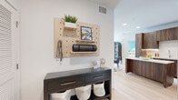 This thoughtfully designed three-bedroom, two-bathroom single-story home in Aurora, Colorado offers a contemporary living experience with stylish finishes throughout. Light hardwood-style flooring flows seamlessly through the main living areas, creating a cohesive and airy feel.

The kitchen is a standout, featuring rich walnut-toned cabinetry that extends to the ceiling, a clean white quartz countertop, a central island for additional prep space, and a full suite of stainless steel appliances — including a French door refrigerator, range, and over-the-range microwave. A white subway tile backsplash adds a crisp finishing touch.

The open living room is defined by a striking bold geometric accent wall in teal and white, complemented by large windows with sheer curtains that welcome abundant natural light and provide access to an outdoor area.

The primary bedroom continues the bold design aesthetic with a dramatic angled accent wall in deep navy and white. A ceiling fan, large window with neighborhood views, and plush carpeting make this a comfortable retreat. The bedrooms are supported by two well-appointed bathrooms, each featuring walnut vanity cabinetry, white quartz countertops, and light tile flooring.

A functional entryway with built-in pegboard storage and two hallway closets round out this modern, move-in ready home.