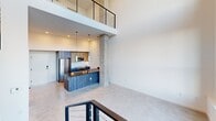 Located at 1502 S Fawcett Ave in Tacoma, WA, this contemporary two-story loft delivers striking modern design across two thoughtfully arranged levels. The main floor immediately impresses with soaring double-height ceilings and an expansive wall of black-framed, floor-to-ceiling windows that bathe the open-plan living area in abundant natural light while offering views of the surrounding neighborhood. Polished concrete floors throughout the lower level reinforce the industrial-modern aesthetic, complemented by a sculptural exposed concrete column that anchors the space.

The kitchen features dark wood cabinetry, a sleek dark countertop island with pendant lighting above, and stainless steel appliances — creating a sophisticated and functional cooking area that flows seamlessly into the living space. A striking open staircase with a black steel frame, wood treads, and cable railings serves as a design centerpiece connecting both floors.

The upper level houses the generously sized primary bedroom, complete with light wood flooring, a wall-mounted mini-split system, and open railing overlooking the main floor below. Three closets — including a walk-in with built-in wire shelving — provide ample storage. A full bathroom with matte black fixtures and a warm-toned entry door with bold hardware complete this well-appointed Tacoma loft.