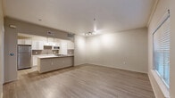 Located in Dallas, TX, this thoughtfully designed 1-bedroom, 1-bathroom residence offers a functional and modern single-level layout. Light-toned wood-style flooring runs throughout, complementing the neutral color palette that creates a clean, cohesive aesthetic.

The open-concept living area is bright and spacious, featuring crown molding, a large window with blinds, and a track lighting fixture. It flows seamlessly into the kitchen, which is equipped with white shaker-style cabinetry, a subway tile backsplash, stainless steel appliances including a full-size refrigerator and built-in microwave, and a peninsula with a white countertop — perfect for casual dining or meal prep. Pendant lighting adds a polished finishing touch overhead.

The bedroom is a comfortable retreat with a ceiling fan, vertical blinds allowing natural light, and access to a walk-in closet outfitted with wire shelving for organized storage. Two additional closets provide generous storage throughout the unit.

The bathroom features white cabinetry, a large vanity mirror, brushed nickel fixtures, and wood-style tile flooring, maintaining the home's clean and modern design language.

A dedicated laundry area houses a full-size washer and dryer alongside upper cabinetry and wire shelving, adding everyday convenience to this well-rounded residence.