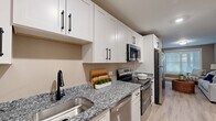 Located at 1551 Johnson Ferry Rd in Marietta, Georgia, this thoughtfully designed one-bedroom, one-bathroom residence makes excellent use of its compact footprint. The interior is finished with warm neutral tones throughout, creating a cohesive and inviting atmosphere from room to room.

The kitchen is a standout feature, outfitted with granite countertops in a classic salt-and-pepper finish, crisp white shaker cabinetry with matte black hardware, and a full suite of stainless steel appliances including a refrigerator, electric range, microwave, and dishwasher. A deep stainless sink with a matte black faucet adds a modern touch.

The living room offers light wood-look flooring, a large window that draws in natural light, and enough space for comfortable seating and entertainment. The bedroom is generously proportioned, featuring plush carpeting, multiple windows including a bay-style arrangement that brightens the room, a private exterior door, and a dedicated closet with paneled double doors.

A dedicated laundry area with matching granite countertops, white cabinetry, and a utility sink provides added convenience. The bathroom includes a clean, white tub-shower combination with matte black fixtures. Throughout the space, consistent finishes and a neutral palette create a polished, move-in-ready environment.