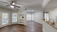 Located in Austin, TX, this two-story, 3-bedroom, 3-bathroom home offers a well-designed layout spread across two floors. The main level features an open-concept living room and kitchen area, where rich hardwood-style flooring flows throughout. The living room stands out with elegant crown molding, a ceiling fan, built-in white shelving, and multiple windows that invite abundant natural light. French doors provide access to the exterior, enhancing the airy feel of the space. The kitchen is appointed with dark espresso cabinetry, granite countertops, and stainless steel appliances, including a dishwasher, offering both style and functionality. Hallways connect the rooms seamlessly, featuring arched architectural details and additional built-in shelving for storage. The bathrooms are finished with granite-topped vanities, dark wood cabinetry, and hardwood-style flooring, with windows providing natural ventilation. Upstairs, the three bedrooms are carpeted for comfort and each features ceiling fans and windows with natural light. The primary bedroom includes a walk-in closet with wire shelving, while additional bedrooms offer built-in closet storage. The overall design presents a cohesive, neutral palette with warm finishes throughout.