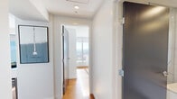 Located at 655 Centre St S in Calgary, this contemporary 2-bedroom, 2-bathroom residence offers a thoughtfully designed single-floor layout with a clean, modern aesthetic throughout. Warm hardwood flooring flows through the open-concept living and kitchen areas, creating a cohesive and inviting atmosphere.

The kitchen is efficiently arranged in a U-shaped configuration, featuring flat-front white cabinetry extending to the ceiling, a neutral stone-toned countertop, a taupe tile backsplash, and stainless steel appliances including a built-in oven and integrated refrigerator. It connects seamlessly to the living area, which benefits from abundant natural light.

Both bedrooms are bright and well-proportioned, with the primary bedroom showcasing dramatic floor-to-ceiling windows that frame sweeping, elevated views of the Calgary skyline and surrounding cityscape. The second bedroom also enjoys generous natural light and closet storage.

The two bathrooms are finished to a high standard, featuring marble-effect porcelain tile flooring and wall accents, floating white vanities with square undermount sinks, and large format mirrors. The ensuite includes a glass-enclosed shower. Hallways are clean and uncluttered, with modern dark-framed interior doors adding a refined contrast to the crisp white walls throughout.