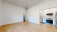 Located at 2103 3rd Street in Santa Monica, CA, this thoughtfully designed single-floor studio maximizes every square foot with a clean, modern aesthetic. The open living area immediately impresses with soaring ceilings and recessed lighting that amplify the sense of space. Light-toned hardwood flooring runs throughout, complementing the crisp white walls and creating a bright, airy ambiance. A wide, black-framed window floods the living area with natural light and offers views of the surrounding neighborhood. The kitchen is efficiently appointed with white shaker-style cabinetry, white quartz countertops, and a full suite of stainless steel appliances, including a refrigerator, range, over-the-range microwave, and dishwasher. A dedicated closet provides convenient built-in shelving for organized storage. The bathroom stands out as a refined retreat, featuring a glass-enclosed walk-in shower adorned with large-format hexagonal wall tiles in warm neutral tones and a decorative mosaic tile floor. A built-in bench adds both comfort and style. The overall design is cohesive and contemporary, making this Santa Monica studio an efficient and elegant urban living space.