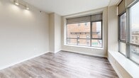 Located at 66 Main Street in downtown Yonkers, NY, this well-appointed 2-bedroom, 2-bathroom residence offers a thoughtfully designed layout with modern finishes throughout. Light gray wood-tone flooring flows consistently across the living spaces, creating a cohesive and contemporary aesthetic.

The open-concept kitchen is a standout feature, equipped with stainless steel appliances including a refrigerator, electric range, and over-the-range microwave. Warm honey-toned cabinetry pairs with dark granite countertops and a tile backsplash, while a peninsula counter opens to the living area. Floor-to-ceiling windows flood the kitchen and living spaces with natural light and frame views of the surrounding Yonkers cityscape.

Both bedrooms are generously sized with neutral walls and large windows that continue the urban view theme. The spacious primary bedroom includes a walk-in closet outfitted with dual wire shelving systems for ample storage. A second closet serves the additional bedroom.

The two bathrooms mirror each other in design, featuring slate-toned tile flooring, white vanities with clean-lined cabinetry, wall-mounted medicine cabinets, and Hollywood-style vanity lighting. One bathroom includes a walk-in shower, while the other offers a full tub and shower combination.