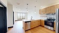 Located in Louisville's vibrant downtown at 320 S Shelby St, this well-appointed one-bedroom, two-bathroom apartment on the fifth floor offers a thoughtfully designed living space with modern finishes throughout. Light hardwood flooring flows seamlessly across the entire unit, complemented by crisp white walls and bold dark baseboards that create a clean, contemporary aesthetic.

The open-concept kitchen serves as the heart of the unit, featuring warm natural wood cabinetry, white quartz countertops, a white subway tile backsplash, and a full suite of stainless steel appliances including a refrigerator, range, and dishwasher. A peninsula island with pendant lighting above connects the kitchen to the living area, making it ideal for both cooking and entertaining.

The bedroom is a comfortable, well-proportioned retreat with a large multi-pane window fitted with a roller shade, offering views of the surrounding Louisville cityscape and greenery. The space receives generous natural light throughout the day.

Both bathrooms feature stylish dark hexagonal tile flooring, natural wood vanities with white countertops, black-framed mirrors, and contemporary wall-mounted lighting fixtures, delivering a cohesive and modern design. The unit also includes a dedicated closet for additional storage.