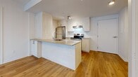 Located at 329 Boul Hymus in Pointe-Claire, Quebec, this well-appointed 2-bedroom, 1-bathroom unit offers a thoughtfully designed layout across a single floor. The open-concept living and kitchen area serves as the heart of the space, featuring warm light wood flooring, a peninsula-style kitchen island with a stainless steel sink and integrated dishwasher, and crisp white cabinetry that extends to the ceiling for generous storage. Stainless steel appliances, including a refrigerator and electric range, complete the kitchen. Large windows in the living area allow abundant natural light to flow through, and a wall-mounted air conditioning unit ensures year-round comfort. The spacious primary bedroom offers a bright window with exterior views and ample room to furnish comfortably. The second bedroom is equally well-lit, with warm hardwood-style flooring and convenient access to the rest of the unit. Two closets provide practical storage solutions throughout. The bathroom features neutral tile flooring, a vanity with a countertop sink, and a clean, understated design. The overall aesthetic is modern and bright, with a consistent palette of whites and natural wood tones that create a cohesive, welcoming atmosphere.