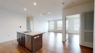 Located at 549–551 New Park Ave in West Hartford, Connecticut, this single-floor residence offers a thoughtfully designed open-concept layout with clean, modern finishes throughout. The living and kitchen areas flow seamlessly together, anchored by warm hardwood-style flooring that extends through the majority of the unit. Recessed lighting illuminates the space, complementing the natural light that filters in through multiple windows fitted with blinds.

The kitchen is a standout feature, equipped with dark espresso cabinetry, granite countertops, and a full suite of stainless steel appliances including a refrigerator, range, microwave, and dishwasher. A central island with seating provides both additional prep space and a casual dining area, making the kitchen as functional as it is stylish.

The bedrooms are bright and well-proportioned, with large windows offering outdoor views and continuing the hardwood-style flooring found throughout. One room features a distinctive teal accent wall, adding a touch of color to the otherwise neutral palette. A dedicated in-unit stacked washer and dryer adds everyday convenience.

The bathroom is finished with large-format tile flooring, dark cabinetry with granite countertops, and a full soaking tub with overhead shower. The overall ambiance is clean, contemporary, and move-in ready.