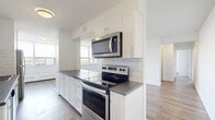 Located at 3390 Keele Street in Toronto's north end, this well-appointed unit offers three bedrooms, two bathrooms, and a thoughtfully designed open layout. Light wood laminate flooring runs throughout, complementing the clean, white walls that give the space a bright and airy feel.

The living room is generously sized, bathed in natural light through large, floor-to-ceiling windows with views of the surrounding greenery. Baseboard heating runs along the perimeter, and a light blue accent door adds a subtle touch of character.

The kitchen features crisp white shaker-style cabinetry, a white subway tile backsplash, dark quartz countertops, a stainless steel refrigerator, and a peninsula that opens toward the living area — ideal for both cooking and entertaining.

The primary bedroom is comfortably proportioned, with a large window overlooking treetops, providing natural light and a calm outdoor view. The additional bedrooms are bright and well-sized, each with light flooring and clean white finishes.

Both bathrooms are finished in a modern style. One features full subway tile surrounding a soaking tub, while the second includes a dark wood vanity with a light stone countertop, tiled flooring, and a wall-mounted mirror with contemporary lighting. The overall ambiance of the unit is clean, modern, and move-in ready.