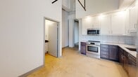 Located at 104 E Second St in Richmond, VA, this single-floor space showcases a distinctive industrial aesthetic throughout. The open layout is anchored by soaring ceilings that expose overhead ductwork and structural elements, lending the space a loft-like character with generous vertical volume.

The kitchen is a standout feature, outfitted with a two-tone cabinet design pairing crisp white upper cabinets with rich, dark lower cabinetry. Light stone countertops, a classic subway tile backsplash, and a full suite of stainless steel appliances — including an electric range, built-in microwave, and dishwasher — complete the functional and stylish cooking space.

The main living areas feature polished concrete flooring throughout, reinforcing the industrial character while providing a durable, low-maintenance surface. Tall white walls and an abundance of recessed lighting keep the interior bright and airy.

The bathroom is well-appointed with a white vanity topped by a dark granite countertop, a full soaking tub with tiled surround, brushed nickel fixtures, and grab bars for added convenience. Additional storage is provided by a walk-in closet accessible from the main living area. An electrical panel is conveniently integrated into the living space, and the overall layout offers a flexible, open floor plan suited to a variety of uses.