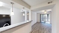 This single-story residence offers a thoughtfully designed layout across two bedrooms, two bathrooms, a kitchen, dining room, hallway, dedicated laundry area, and two closets. The open-concept living and dining area features wood-look flooring throughout and a textured ceiling, creating a cohesive and clean aesthetic. A standout architectural detail is the pass-through kitchen window with a granite-style countertop overhang, accented by pendant lighting that adds a stylish touch while maintaining a connection between the kitchen and living spaces. Sliding glass doors in the living area invite natural light and provide access to an outdoor space.

The kitchen is equipped with black appliances and benefits from the same bright, neutral palette found throughout the unit. Both bedrooms are comfortably sized — the primary bedroom offering generous square footage — each featuring wood-look flooring, ceiling fans with lighting, and windows with natural light. Both bathrooms include tub-shower combinations, granite-style vanity countertops, and wood-look tile flooring, maintaining a consistent design language.

The dedicated laundry area houses a full-size washer hookup and water heater, providing practical in-unit convenience. With neutral tones, consistent finishes, and a functional floor plan, this residence delivers a clean, move-in-ready living environment.