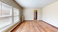 Located at 2425 Delaware Ave in Buffalo, NY, this one-bedroom, one-bathroom unit offers a well-organized layout across a single floor. Warm hardwood flooring runs throughout the space, lending a cohesive and inviting character to every room. A charming arched entryway connects the hallway to the living area, adding a touch of architectural elegance. The living room is a comfortable open area filled with natural light from large windows dressed with blinds, and features a classic cast-iron radiator that adds to the space's vintage charm. The kitchen is efficiently appointed with oak cabinetry, dark granite-style countertops, a gas range, and a white refrigerator, along with a window that brings in additional natural light. The bedroom is a quiet, private retreat with its own window and closet access. Three closets throughout the unit provide ample storage. The bathroom showcases a classic aesthetic with black-and-white mosaic tile flooring, tiled walls with decorative border accents, a full bathtub with shower, vanity, and a small window for ventilation. The drop-panel ceilings in select areas complement the neutral, warm-toned walls found throughout this functional and characterful Buffalo home.