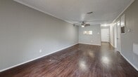 Located at 1111 Honeysuckle Way in Arlington, TX, this 2-bedroom, 2-bathroom single-floor residence offers a well-organized layout designed for comfortable everyday living. Rich, dark hardwood-style flooring runs consistently throughout the home, creating a warm and cohesive aesthetic against the neutral gray walls and crisp white trim.

The open living area is highlighted by crown molding, a textured ceiling, and a ceiling fan with a light fixture. A pass-through window connects the living space to the kitchen, enhancing the open feel, while a sliding glass door floods the room with natural light and provides access to an outdoor balcony.

The kitchen is well-appointed with bright white shaker-style cabinetry featuring matte black hardware, light countertops, a stainless steel sink, and black appliances, offering both style and functionality.

The primary bedroom is a generously sized retreat with its own ceiling fan and direct access to an en-suite bathroom featuring white cabinetry and a tub-shower combination. The second bedroom is also well-proportioned, with a ceiling fan and a window that brings in natural light. A hallway connects the private areas of the home, which also include a dedicated closet and a second full bathroom.