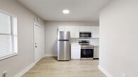 Located at 1315 NE Miami Ct in Miami, FL, this one-bedroom, one-bathroom unit offers a well-organized and efficiently designed single-floor layout. The open-concept kitchen serves as the centerpiece of the living area, featuring a full suite of stainless steel appliances including a refrigerator, electric range, microwave, and dishwasher. White shaker-style cabinetry paired with a subway tile backsplash and light countertops give the kitchen a clean, modern aesthetic. Light wood-tone vinyl flooring runs throughout the entire unit, providing visual continuity and easy maintenance. The bedroom is a cozy, private space fitted with a window-mounted air conditioning unit and a closet rod for hanging storage, with a window that allows natural light to filter in. The bathroom includes a full bathtub and shower combination with white tile surround, a window for natural ventilation, and accessible grab bar hardware. A dedicated closet offers additional storage, and an in-unit stacked washer and dryer adds everyday convenience. The neutral color palette of warm whites and soft grays throughout creates a bright, clean ambiance. The unit's thoughtful layout maximizes every square foot, making it a practical and functional living space in the heart of Miami.