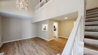 Located at 1008 Rucker St in Greensboro, NC, this two-story residence is thoughtfully designed to maximize its layout across two floors. The main level serves as the heart of the home, where an open living room with soaring ceilings and warm wood-look flooring creates an airy, welcoming atmosphere. Large windows flood the space with natural light and offer views of the surrounding greenery, while a pass-through window connects the living area to the galley-style kitchen. The kitchen features crisp white cabinetry, stainless steel appliances including a refrigerator, microwave, and range, and light-toned countertops—all finished with light wood flooring. A stylish chandelier and a staircase with white balusters anchor the entry area on the main floor. The upper level offers a loft-style open space accessible via the staircase, complete with a distinctive sliding barn door that leads to a well-appointed bathroom featuring a combined tub and shower, a floating vanity, and wood-look flooring. A utility room and closet provide practical storage solutions. The home also includes an outdoor deck with wooden railings, offering a private outdoor retreat with views of a lush, tree-lined backyard—ideal for relaxing or entertaining.
