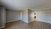 This two-floor residence offers a clean, neutral aesthetic throughout, with warm taupe and gray tones complementing each space. The main living area is open and spacious, featuring durable wood-look plank flooring, crisp white crown molding, and a textured ceiling that adds subtle character. Ample wall outlets and HVAC vents are thoughtfully placed throughout. The living space flows naturally toward a dedicated laundry area, conveniently accessible from the main floor.

The kitchen is a functional highlight, equipped with gray raised-panel cabinetry, granite-style countertops, a classic white subway tile backsplash, a stainless steel sink, and black appliances including a full-size refrigerator. The wood-look flooring continues seamlessly into this space.

The bathrooms are well-appointed: one features a tiled tub-shower combo with clean white fixtures and wood-look flooring, while a second half-bath includes a granite-topped vanity and mirror. Both maintain the consistent neutral color palette found throughout the home.

The upper level bedrooms are finished with plush carpeting, generous closet space, and windows that invite natural light. One bedroom notably features dual closets, offering excellent storage capacity. The textured walls and simple, uncluttered design make each room feel versatile and move-in ready.