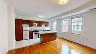 Located on the fifth floor at 811 Quincy Street Northwest in Washington, DC, this one-bedroom, one-bathroom unit offers a well-organized layout with thoughtful finishes throughout. The kitchen is a standout feature, equipped with rich dark wood cabinetry, granite countertops, a stainless steel appliance suite including a gas range, built-in microwave, and refrigerator, as well as an in-unit washer and dryer. A peninsula with a granite surface provides additional prep space and separates the kitchen from the main living area. White tile flooring grounds the kitchen, while warm hardwood floors extend throughout the living and bedroom areas, adding a classic, inviting feel. The bedroom is generously proportioned, featuring a ceiling fan, bright white walls, and windows that draw in natural light with views of surrounding brick architecture. The bathroom is clean and functional, featuring full-height white subway tile surrounding a soaking tub with shower, a single vanity, and tiled flooring. Hallways connect the rooms efficiently, contributing to a practical and comfortable flow throughout the unit.