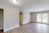 Located at 1606 Pinecroft Rd in Greensboro, NC, this single-floor, 2-bedroom, 1-bathroom home offers a clean and functional layout with a warm, neutral aesthetic throughout. The living room is an open, inviting space featuring light wood-style laminate flooring, neutral beige walls with crisp white baseboards, a textured ceiling, and a window that draws in natural light — creating a bright and airy atmosphere. The layout flows naturally from the living area through a hallway connecting to the rest of the home. The kitchen is well-appointed with white shaker-style cabinetry, light countertops, and a full suite of stainless steel appliances including a gas range, over-the-range microwave, dishwasher, and refrigerator, all set over matching wood-style flooring. Both bedrooms are comfortably sized and share the same cohesive flooring and neutral color palette, each with windows fitted with blinds for natural light and privacy. The primary bedroom includes a generously sized walk-in closet with wire shelving. The full bathroom is clean and functional, featuring a tub/shower combo and an overhead cabinet for storage. A hallway with an additional closet completes the layout, providing practical storage throughout.