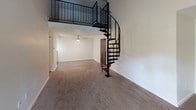 This single-story residence in Comstock Park, Michigan offers a thoughtfully designed layout with a distinctive architectural character. A standout feature of the main living area is the dramatic black metal spiral staircase, which leads to an upper loft space enclosed by matching black metal railings, adding a striking vertical element to the open living space. The living room is anchored by a floor-to-ceiling stone fireplace with a classic arched iron door, flanked by a sliding glass door that invites natural light and outdoor views. Soft carpeting runs throughout the living areas and bedrooms, contributing to a warm, comfortable ambiance.

The kitchen is appointed with crisp white shaker-style cabinetry, granite countertops, stainless steel appliances, and a gray tile backsplash, combining both style and practicality. The bedrooms are well-proportioned, each featuring plush carpet and window blinds that allow for natural light while maintaining privacy.

The bathrooms are finished with granite-topped white vanities, framed mirrors, and brushed nickel fixtures. The full bathroom includes a tub-shower combination with white tile surround and wood-look vinyl flooring, providing a clean and updated aesthetic throughout.