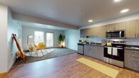 This well-appointed single-floor residence offers a thoughtfully designed open-concept layout that seamlessly connects the kitchen and living areas. The kitchen is a standout feature, equipped with stainless steel appliances including a refrigerator, range, microwave, and dishwasher, complemented by warm wood-tone cabinetry, dark countertops, and recessed lighting overhead. Durable wood-look flooring runs throughout the kitchen and main living space, creating a cohesive and easy-to-maintain environment.

The living area flows naturally toward a private balcony through a glass door flanked by windows, filling the space with natural light and offering outdoor views. Two carpeted bedrooms provide comfortable retreats, each with windows that bring in additional daylight. A flexible secondary room with carpet and a closet offers versatile use as a home office, guest room, or fitness space.

Two full bathrooms serve the residence. One features a vanity with wood-tone cabinetry, dark countertops, and a large mirror, while the second includes a full tub-shower combination with wood-look flooring. Additional storage is available via a walk-in closet off the kitchen area. The overall design balances modern finishes with a warm, inviting ambiance throughout.
