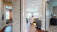 This thoughtfully designed single-floor residence offers a seamless open-concept layout that connects the kitchen, dining, and living areas into one cohesive, light-filled space. Rich hardwood flooring runs throughout the main living areas, anchoring the contemporary aesthetic.

The kitchen is a standout feature, showcasing a two-tone design with crisp white upper cabinetry and slate-gray lower cabinets, complemented by a bright white countertop island, subway tile backsplash, stainless steel appliances, and modern pendant lighting overhead. Recessed lighting and large windows ensure the space is generously illuminated.

The living room is warm and inviting, with multiple windows and a sliding glass door that opens onto a private balcony, offering pleasant views of mature trees. Natural light pours in through sheer curtains, enhancing the airy feel of the space.

The bedroom features plush carpet flooring, a bold navy accent wall, and bold graphic window treatments, lending the room a distinct, stylish character. The primary bathroom is generously proportioned, with dark slate tile floors, a dual-sink gray vanity with white countertops, a separate walk-in shower, and track lighting above a large mirror. A second full bathroom features a tub-shower combination, matching gray cabinetry, and coordinating tile finishes throughout.